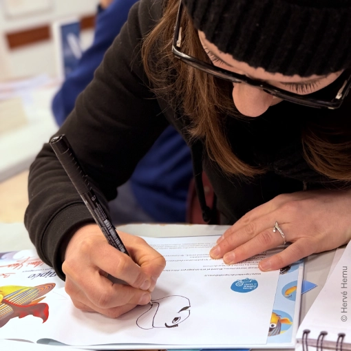 Aline Hernu dédicace son album jeunesse Flipeo le poisson courageux au salon du livre de Don le 1er Février 2026 (dans le Nord en région Hauts-de-France). Auteur et crédit photo : Hervé Hernu. Un livre aux éditions La Petite Fabrique de Livres.